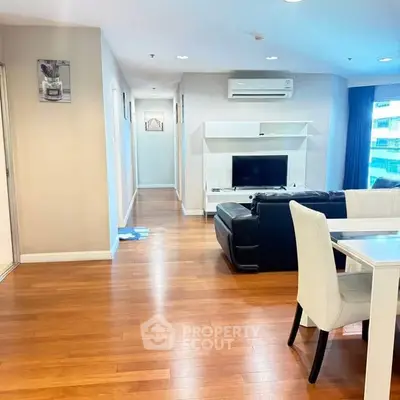 Spacious living room with modern furniture and wooden flooring in a bright apartment.