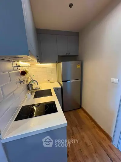 Modern compact kitchen with sleek cabinetry and stainless steel appliances in cozy apartment.