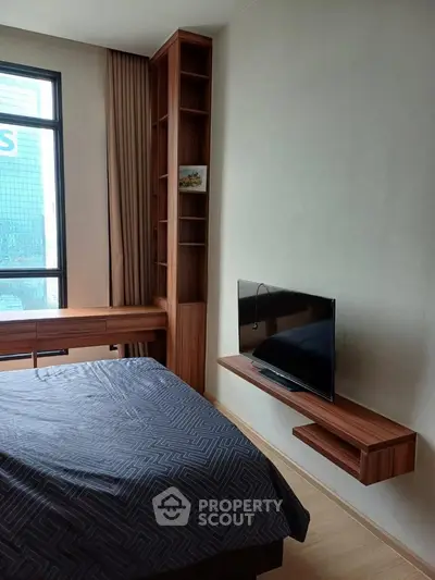 Modern bedroom with sleek wooden furniture and wall-mounted TV, featuring a large window for natural light.