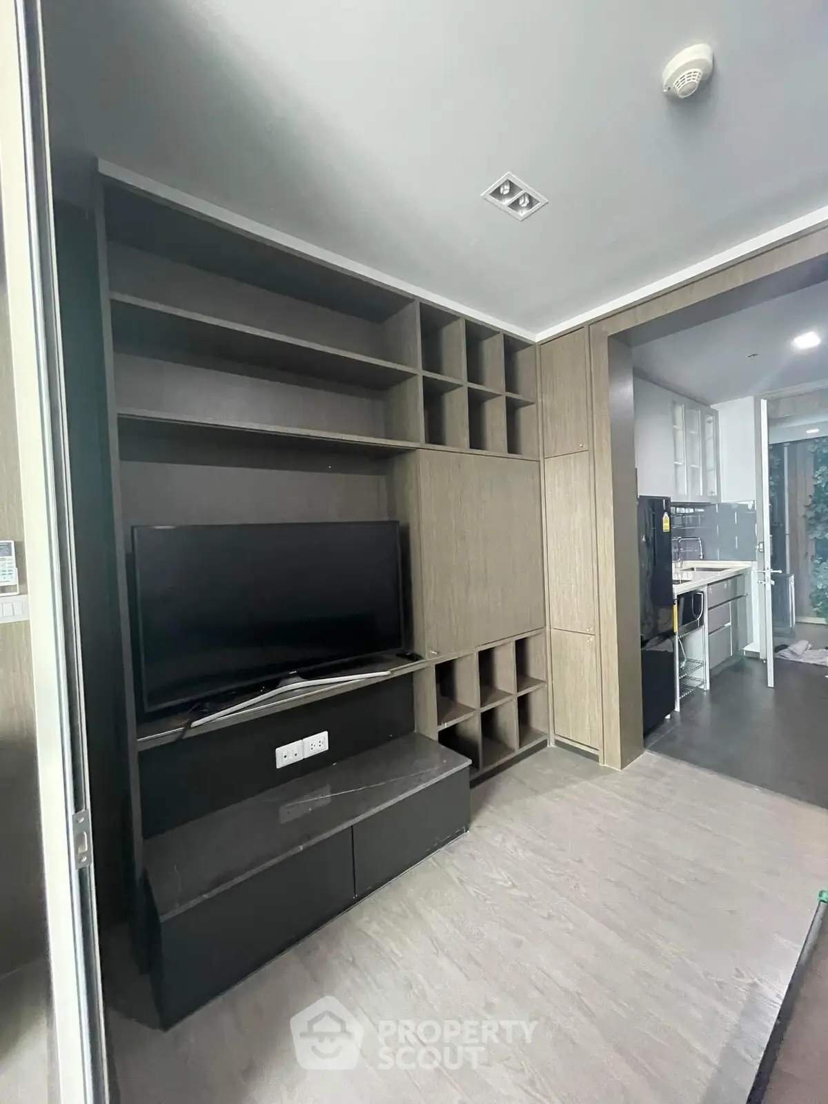 Modern living room with built-in TV unit and sleek kitchen view