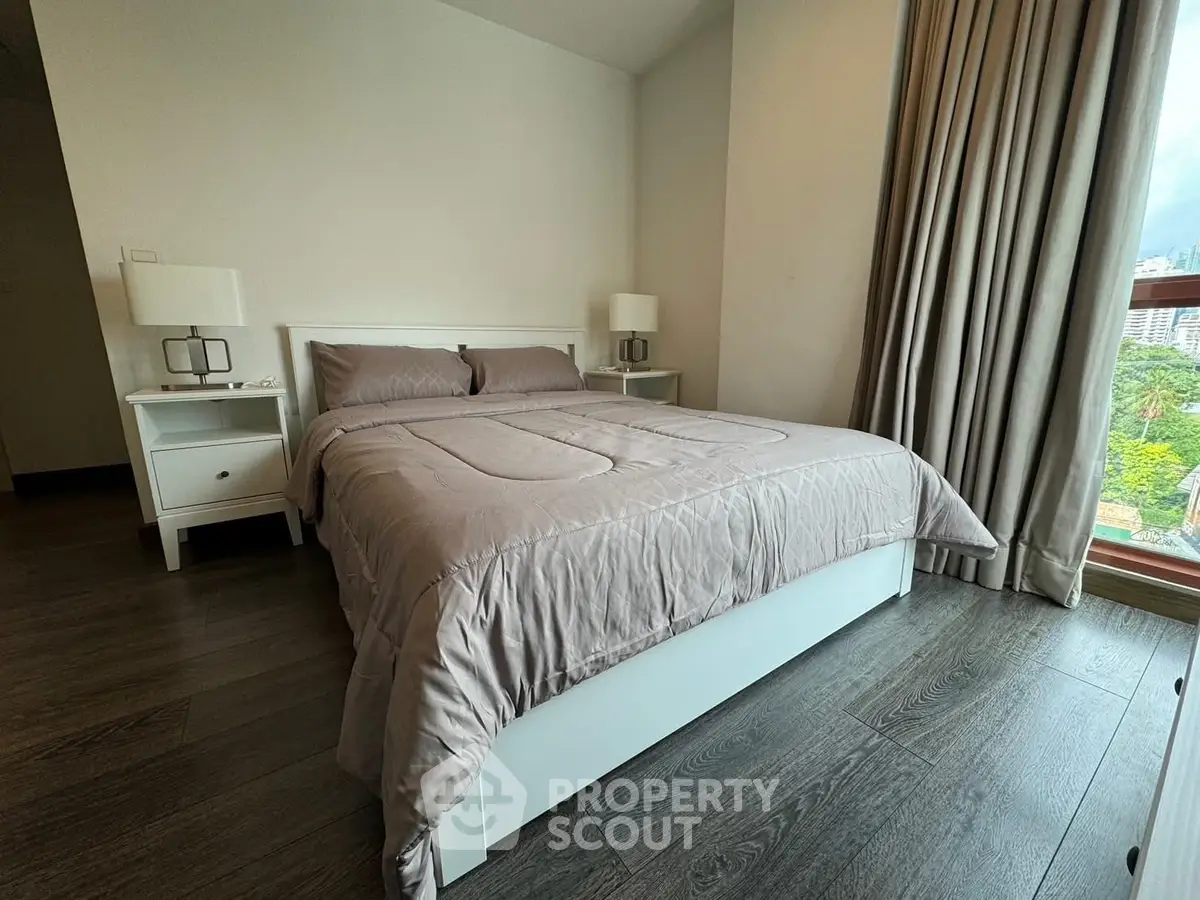 Cozy bedroom with modern decor and large window offering a serene view.