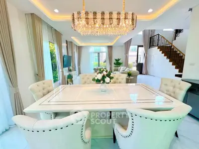 Luxurious open-plan living and dining area with elegant chandelier and plush seating.