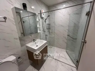 Modern bathroom with glass shower and sleek vanity in contemporary apartment.