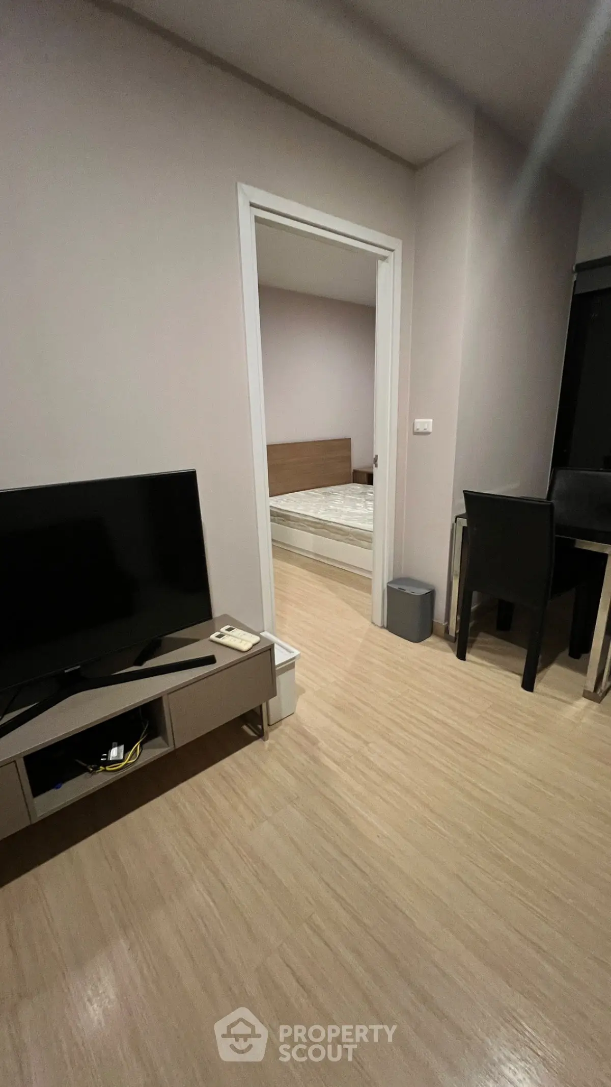 Modern apartment interior with TV, dining area, and glimpse of bedroom.