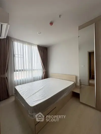 Modern bedroom with natural light, featuring a bed with storage and elegant curtains.