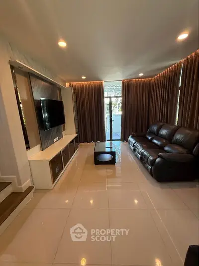 Spacious modern living room with sleek leather sofa and large TV, perfect for relaxation and entertainment.