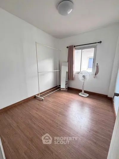 Spacious empty bedroom with wooden flooring and natural light