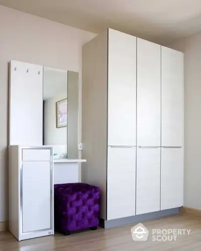 Modern bedroom with sleek white wardrobe and stylish purple ottoman