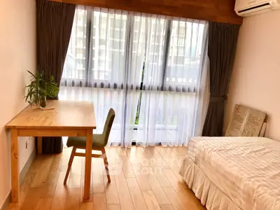 Bright bedroom with wooden flooring, large window, and minimalist decor