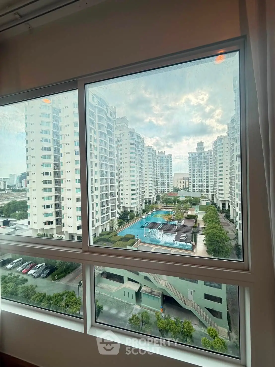 Stunning view of modern high-rise buildings and pool from apartment window.