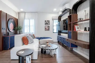 Modern living room with stylish decor and contemporary furniture, featuring a cozy seating area and elegant shelving.