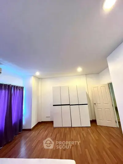 Spacious bedroom with modern wardrobe and wooden flooring