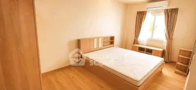 Spacious bedroom with wooden flooring and natural light, featuring a minimalist design and air conditioning.