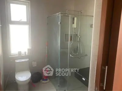 Modern bathroom with glass shower enclosure and large window for natural light.