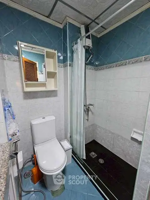 Compact bathroom with modern shower and toilet in blue and white tiles.