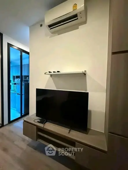 Modern living room with sleek TV setup and air conditioning in stylish apartment.