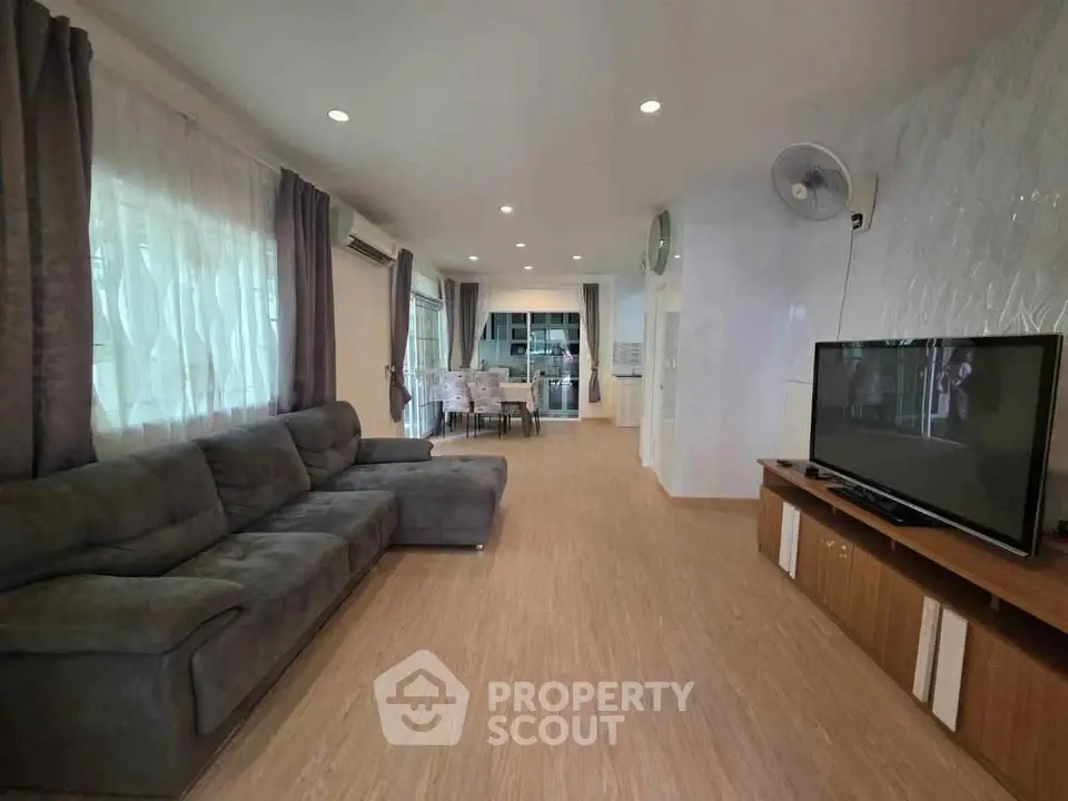 Spacious living room with modern decor and large sofa, perfect for relaxation and entertainment.