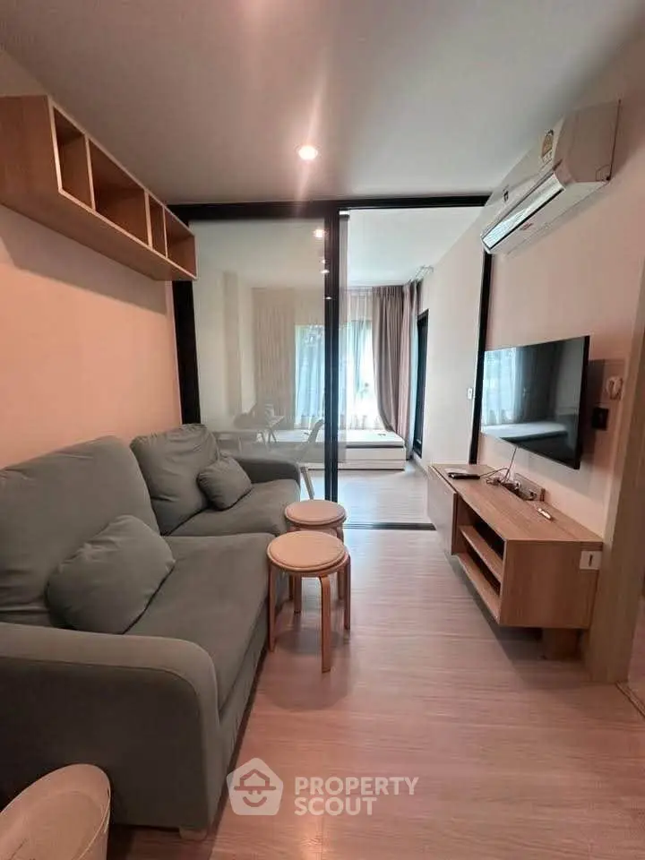 Modern living room with glass partition, cozy sofa, and wall-mounted TV in stylish apartment.