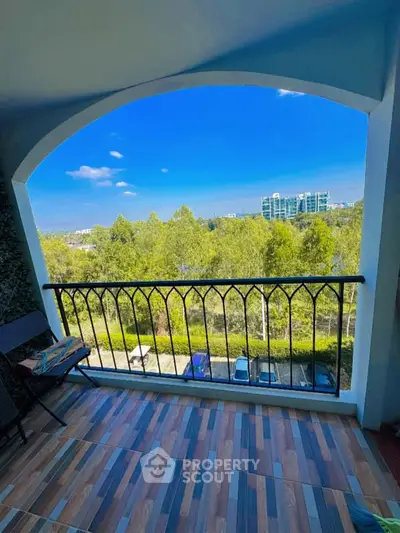 Spacious balcony with scenic view of lush greenery and modern buildings.
