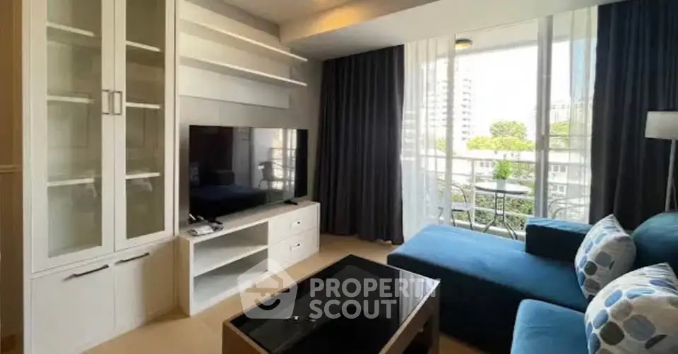 Modern living room with large TV, stylish furniture, and balcony view in urban apartment.