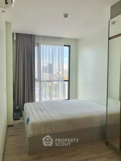 Modern bedroom with large window and city view, featuring a comfortable bed and sleek design.