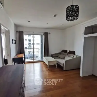 Spacious living room with wooden flooring and balcony access in modern apartment.