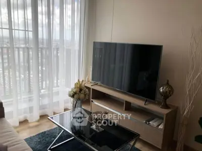 Modern living room with large TV and city view, featuring elegant decor and natural light.
