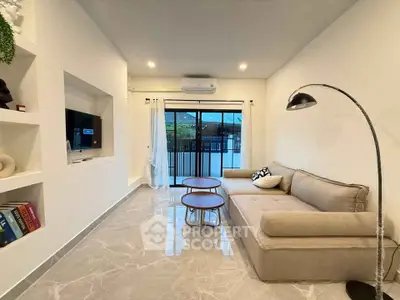 Modern living room with elegant sofa and stylish decor, featuring a sleek floor lamp and large window view.