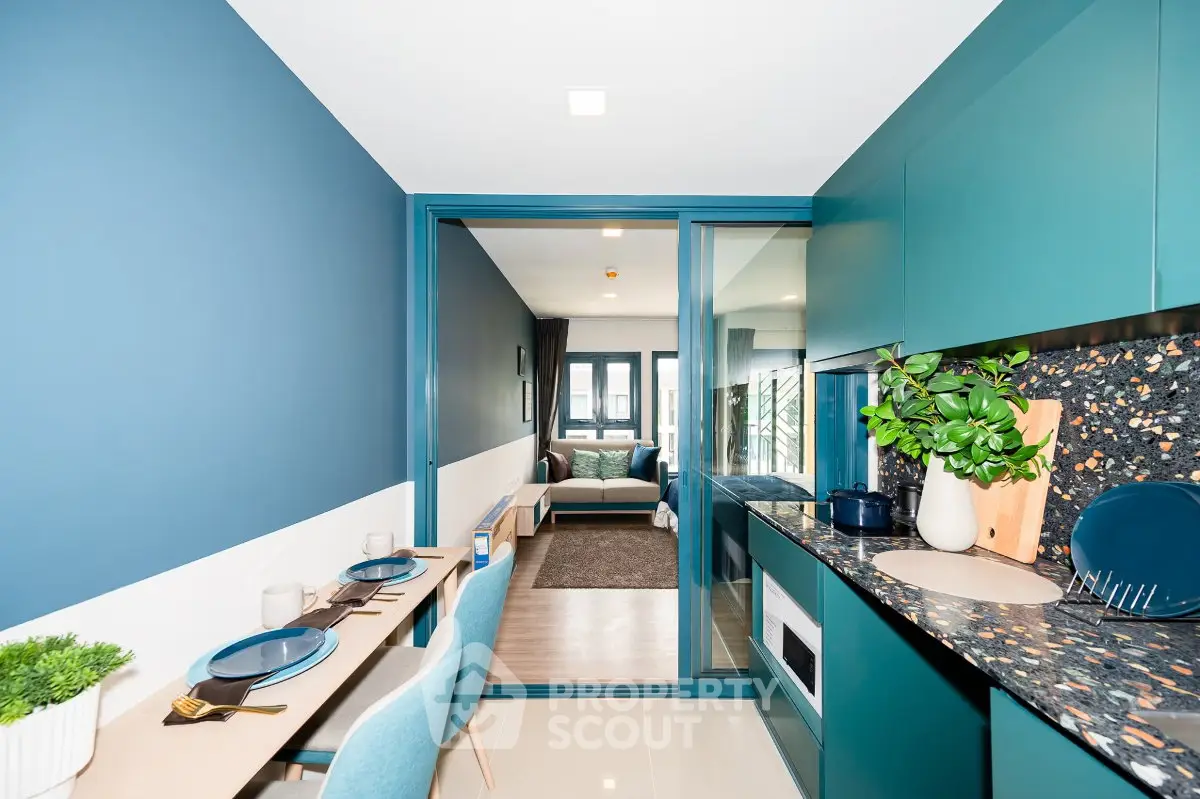 Modern kitchen with open layout and stylish blue decor leading to cozy living room.