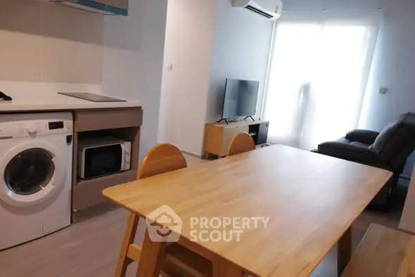 Modern living room with dining area and appliances, featuring a cozy ambiance.