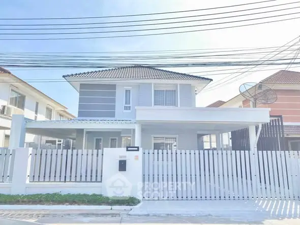 Modern two-story house with gated fence and satellite dish in suburban neighborhood.