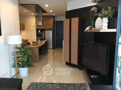 Modern living room with open kitchen, stylish decor, and large TV in a contemporary apartment.