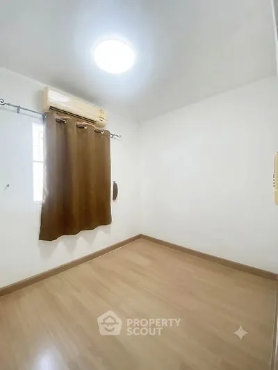 Spacious empty room with wooden flooring and air conditioning, perfect for customization.