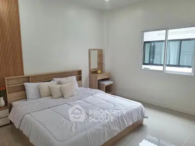 Spacious modern bedroom with elegant decor and large window for natural light.