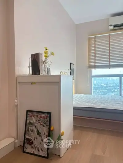 Cozy bedroom with city view, featuring modern decor and natural light.