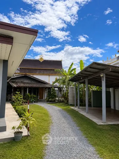 Charming property with lush garden and traditional architecture under a vibrant blue sky.