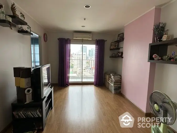 Spacious living room with gleaming hardwood floors, large windows offering city views, and a cozy pink accent wall, perfect for urban living.