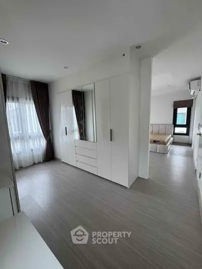 Spacious modern bedroom with elegant white wardrobe and natural light