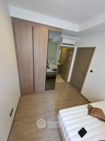 Modern bedroom with wooden flooring, built-in wardrobe, and air conditioning unit.