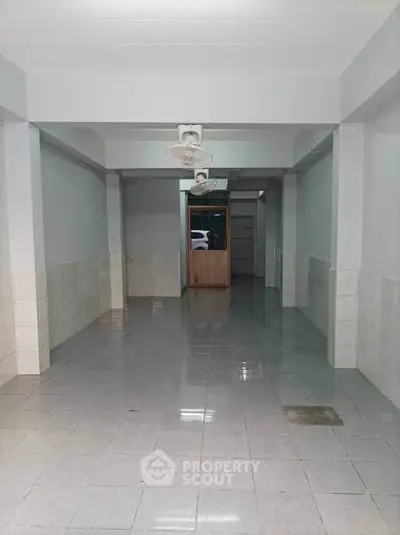 Spacious tiled interior with ceiling fans, ideal for versatile use in real estate.