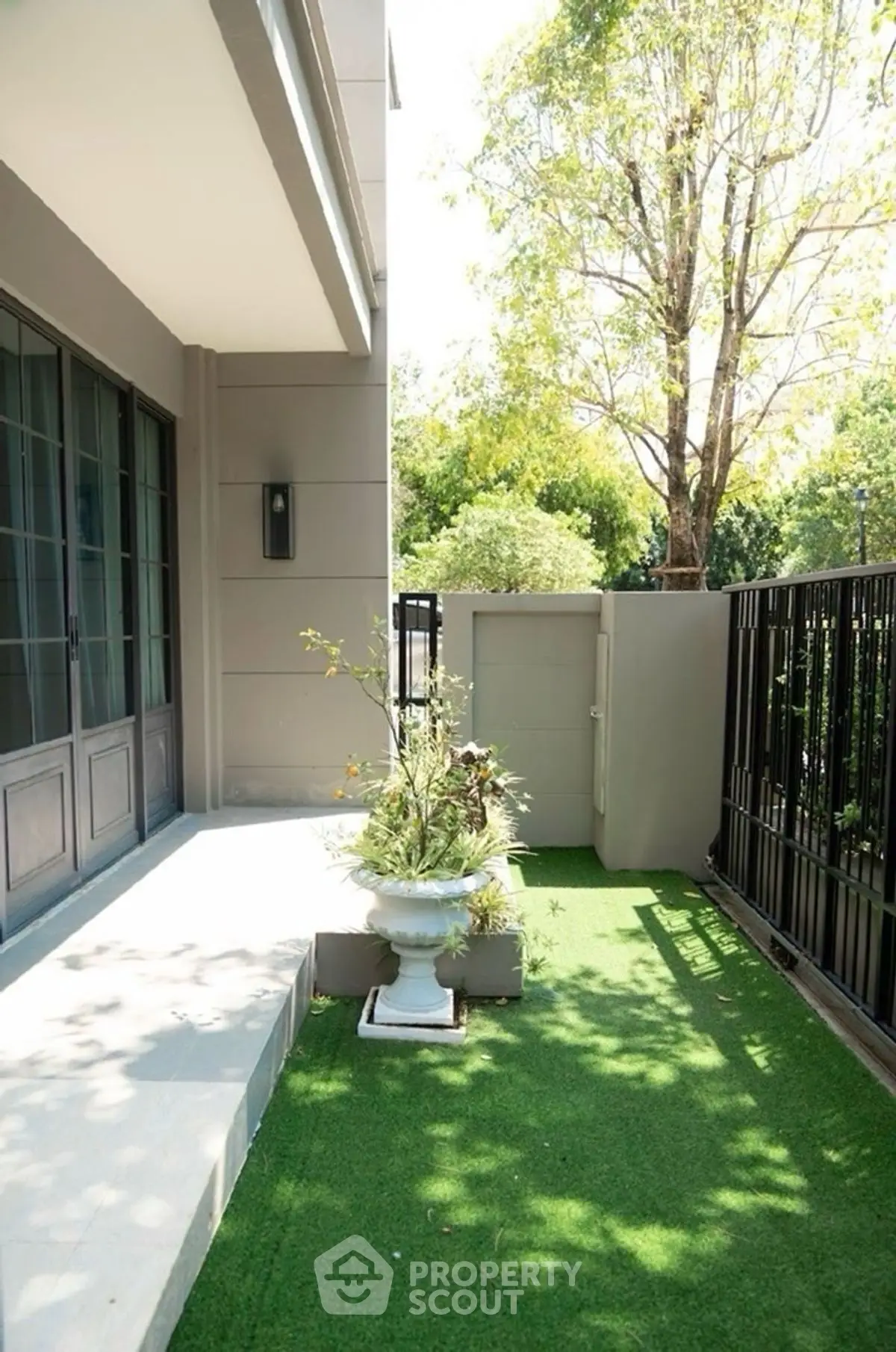 Charming garden area with artificial grass and elegant planter in modern home exterior.
