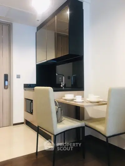 Modern kitchen with sleek cabinetry and cozy dining area in a stylish apartment.
