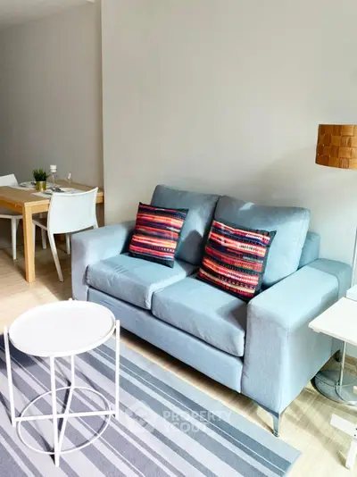 Modern living room with stylish sofa and dining area, featuring vibrant decor and natural light.