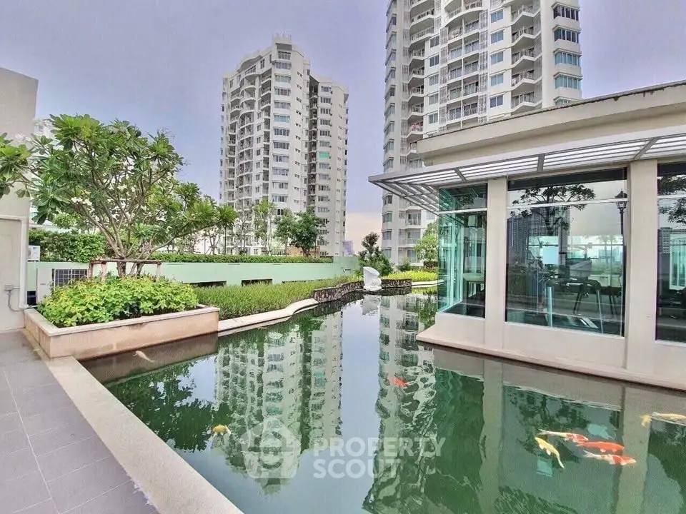 Luxurious high-rise apartment complex with serene koi pond and lush greenery, offering a tranquil urban oasis.