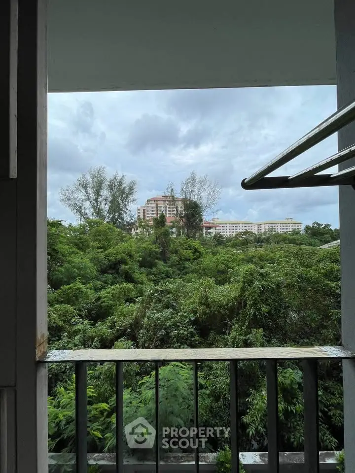 Scenic view from a balcony overlooking lush greenery and distant buildings, perfect for nature lovers.