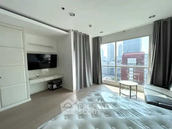 Modern bedroom with city view, featuring large windows and sleek furnishings.