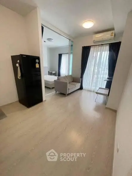 Modern apartment interior with open layout, featuring a cozy living area and large windows for natural light.