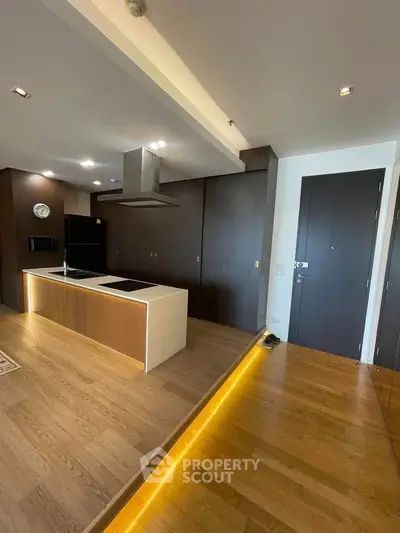 Modern open-layout kitchen with sleek wooden flooring and stylish lighting