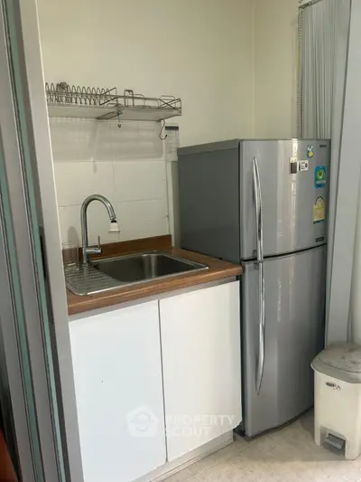 Compact kitchen with stainless steel fridge and modern sink