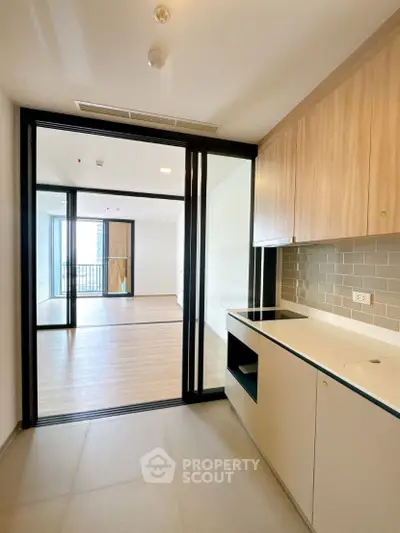 Modern kitchen with sleek cabinetry and open layout leading to spacious living area.